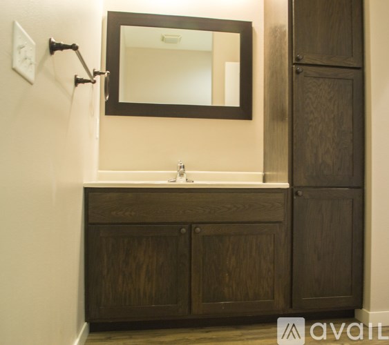 A bathroom with a wooden vanity and a mirror above it.