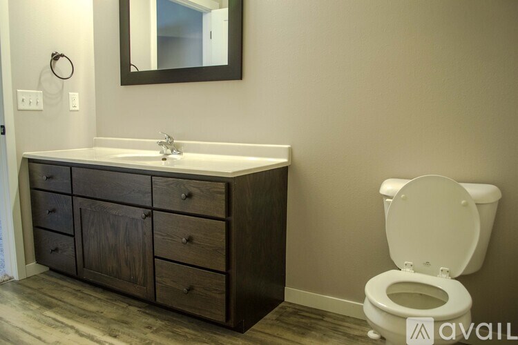 A bathroom with a toilet, sink, and wooden cabinet.