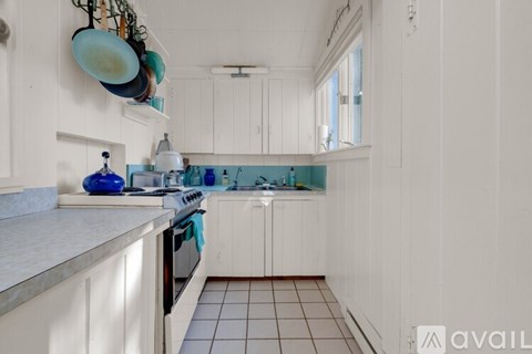 A kitchen with white cabinets and a blue vase on the counter.
