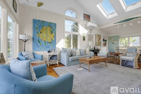 A living room with a blue couch and a painting of a yellow fish on the wall.