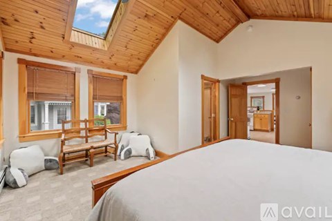 A bedroom with a large bed and a window with blinds.