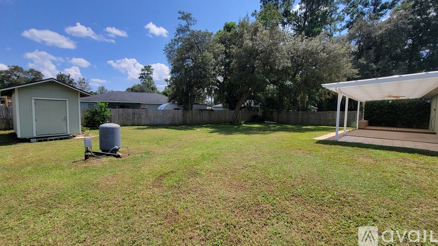 A backyard with a shed, a water heater, and a covered patio area.