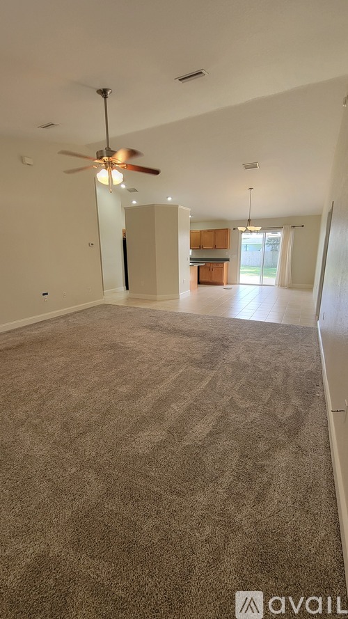 A spacious room with a carpeted floor and a ceiling fan.
