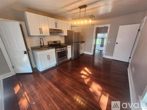 A kitchen with white cabinets and a wooden floor.