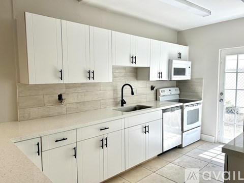 A kitchen with white cabinets and a marble backsplash.