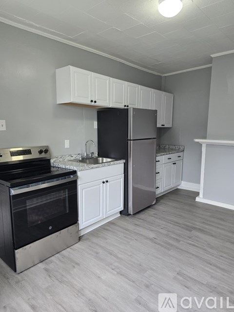 A kitchen with a black refrigerator and stove top oven.