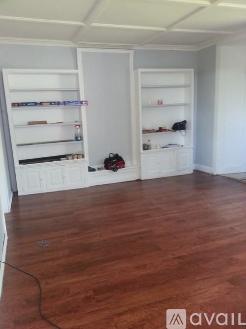 A room with white shelves and a wooden floor.