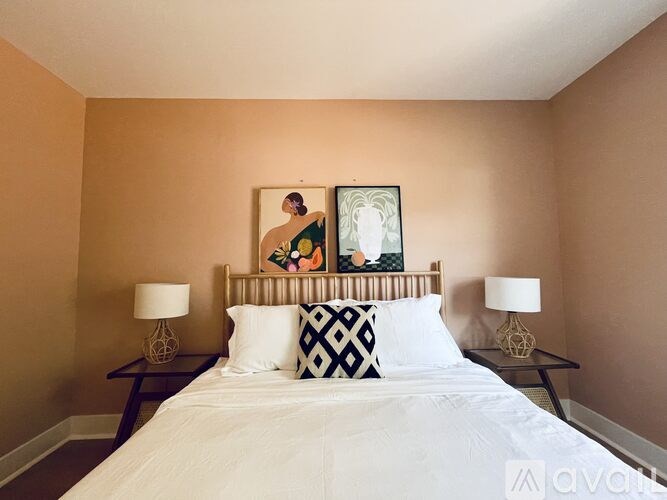 A bedroom with a large bed and two lamps.