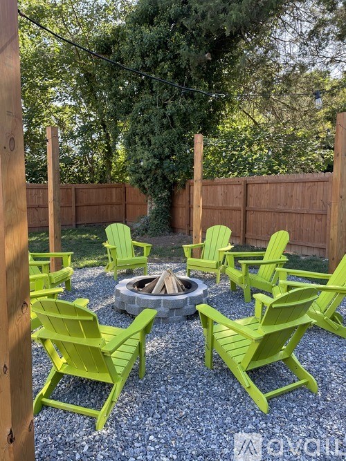 A set of green chairs are arranged around a fire pit.