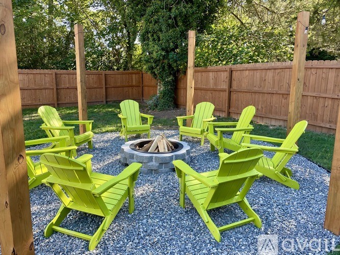A fire pit surrounded by green chairs in a backyard.