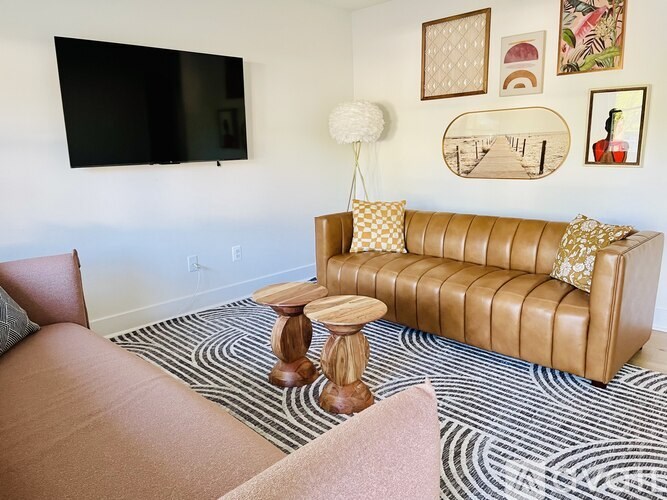 A living room with a tan couch and a wooden stool.
