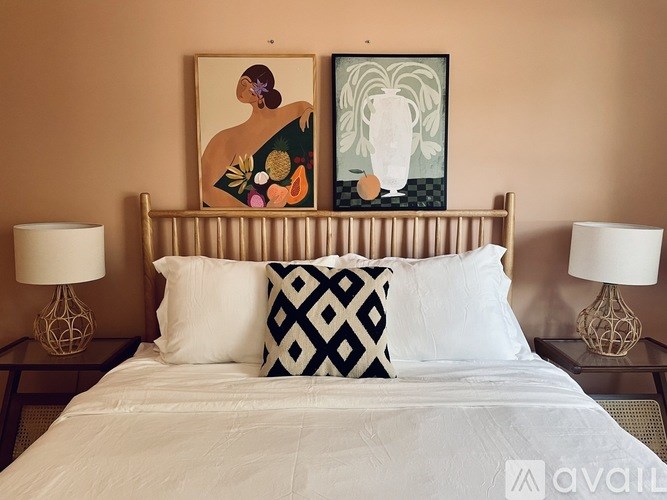 A bed with a white comforter and two decorative pillows.