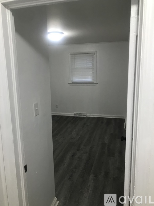 A room with a wooden floor and a window with blinds.