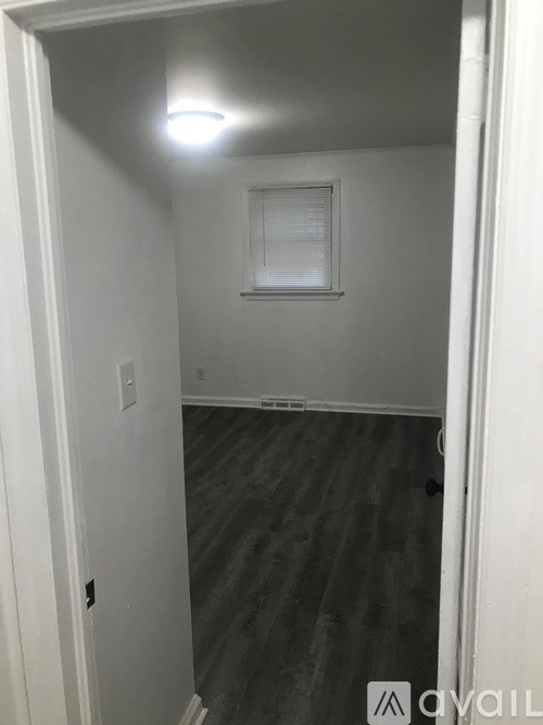 A room with a wooden floor and a window with blinds.