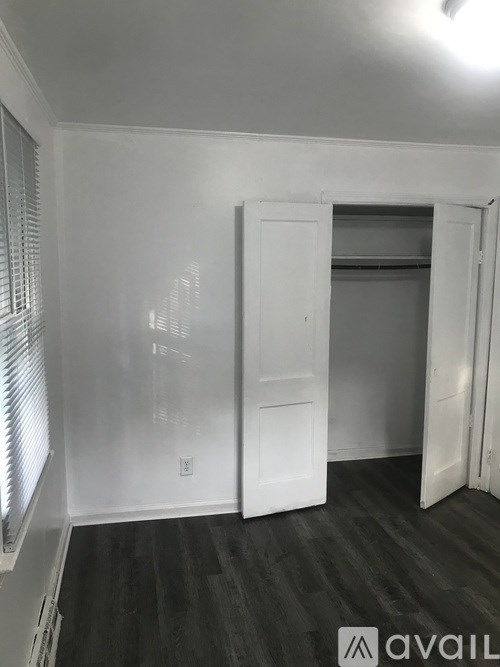 A room with a white door and a window with blinds.