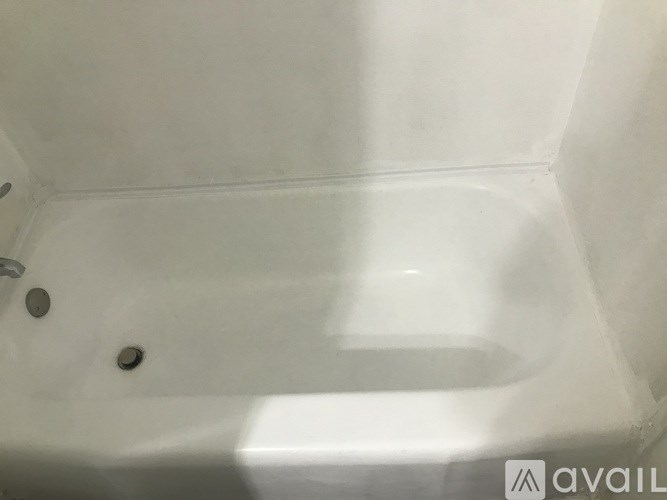 A white bathtub with a drain in the middle.