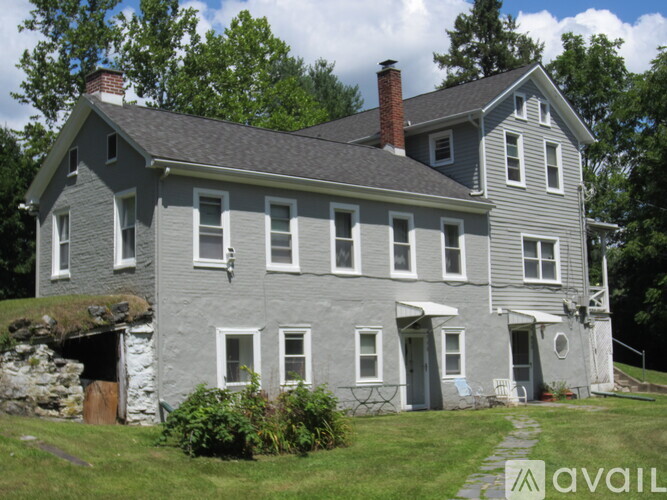 A grey house with a stone wall and a brown door.