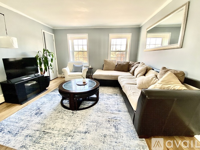 A living room with a white chair and a black ottoman.