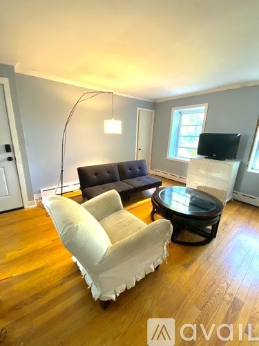 A living room with a white chair and a black ottoman.