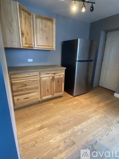 A kitchen with wooden cabinets and a stainless steel refrigerator.