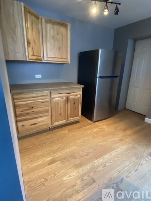 A kitchen with wooden cabinets and a stainless steel refrigerator.