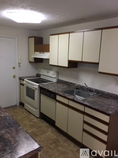 A kitchen with white appliances and brown cabinets.