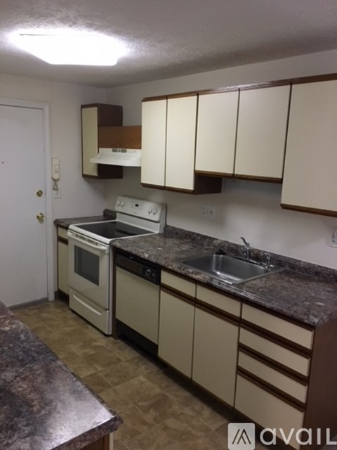 A kitchen with white appliances and brown cabinets.
