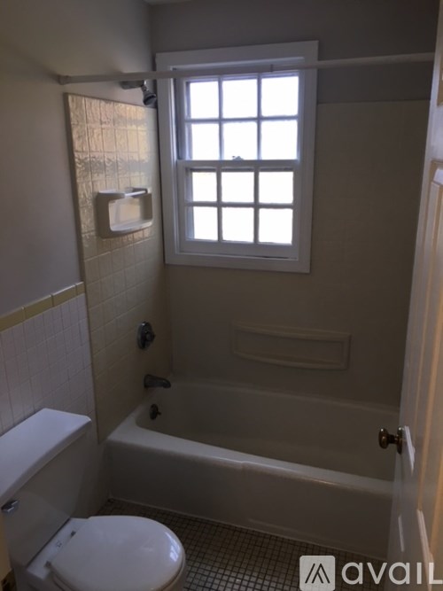 A bathroom with a toilet, tub, and window.