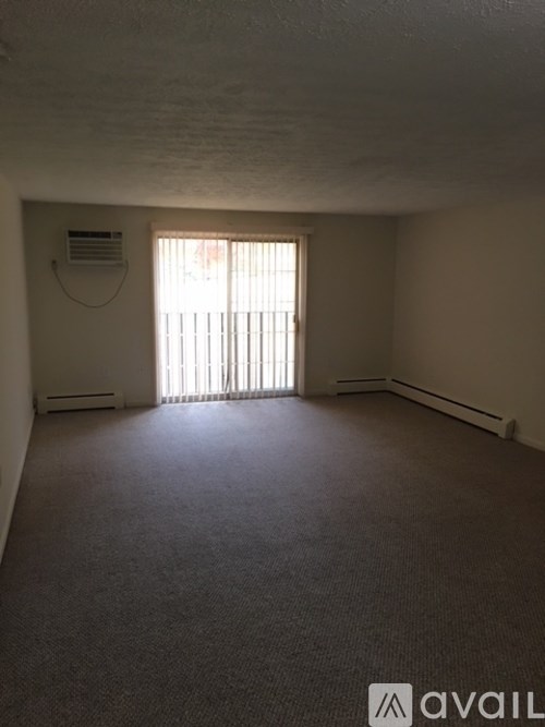 A room with a carpeted floor and a window with blinds.
