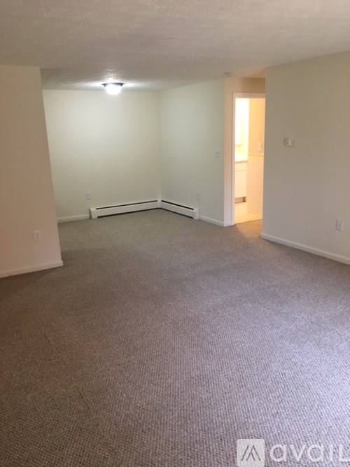 A carpeted room with a doorway leading to another room.