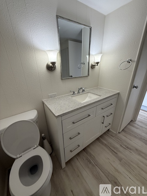 A white bathroom with a shower curtain and a wooden floor.