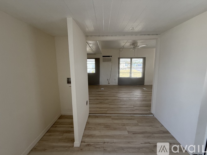 A spacious room with wooden flooring and white walls.