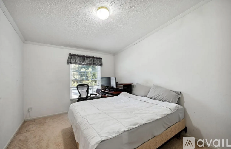 A bedroom with a bed, nightstand, and window with a view of trees.