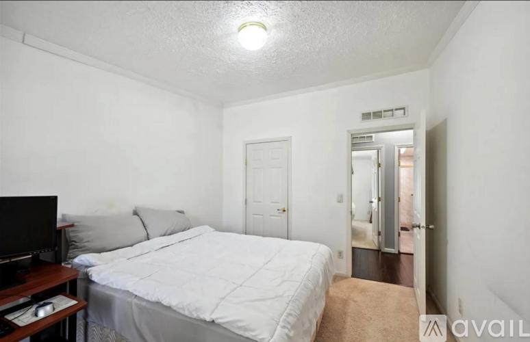 A bedroom with a bed, a television, and a carpeted floor.
