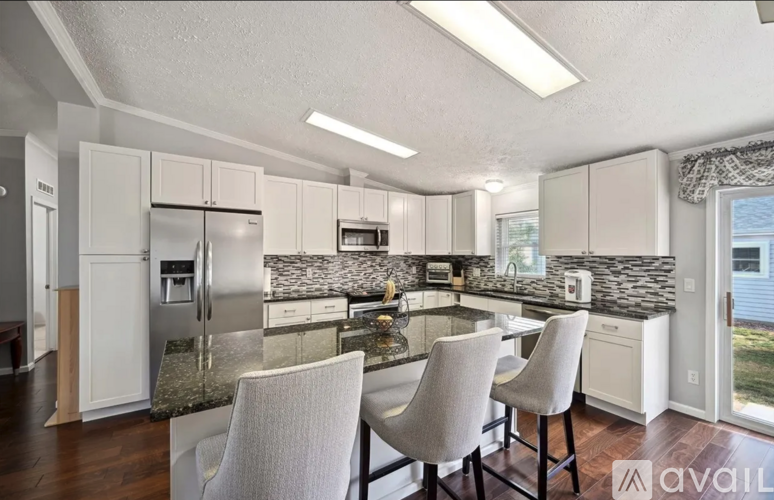A kitchen with white cabinets and a granite countertop.