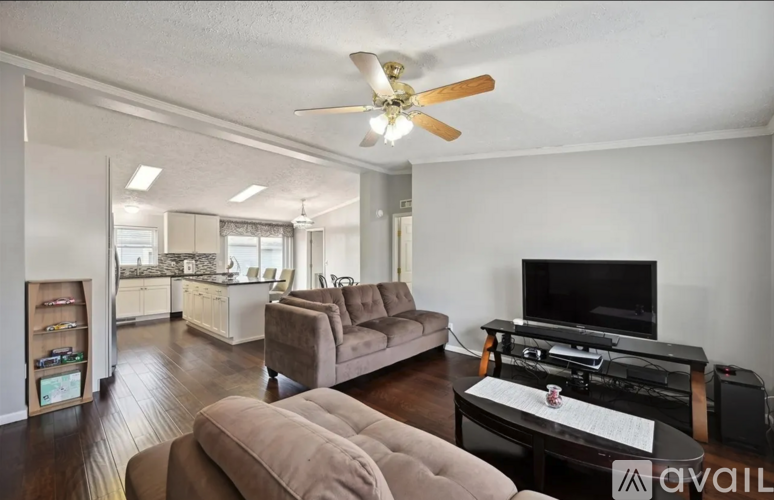 A living room with a brown couch and a television on a black stand.