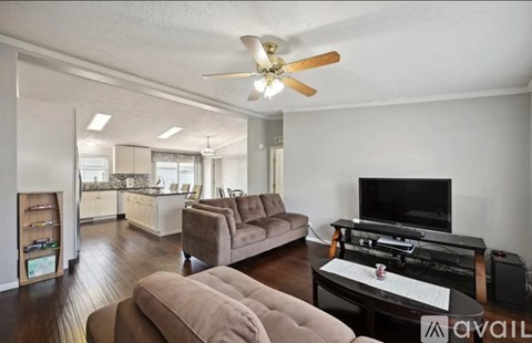 A living room with a brown couch and a television on a black stand.