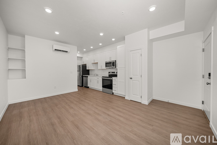 A spacious kitchen with white cabinets and a wooden floor.