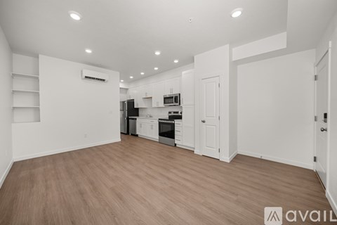 A spacious kitchen with white cabinets and a wooden floor.