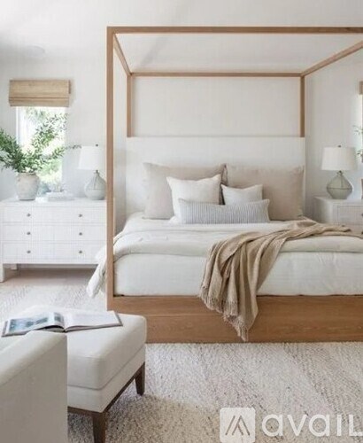 A bedroom with a large bed, a bench, and a window.