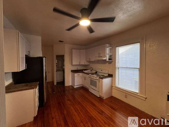 A kitchen with white cabinets and a black refrigerator.