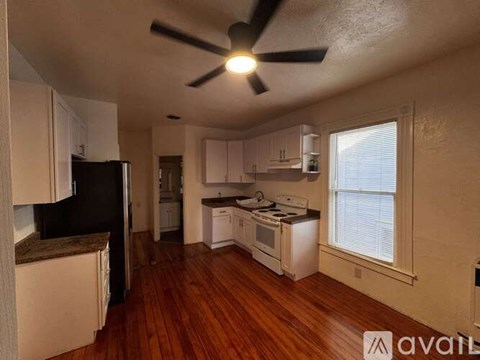 A kitchen with white cabinets and a black refrigerator.