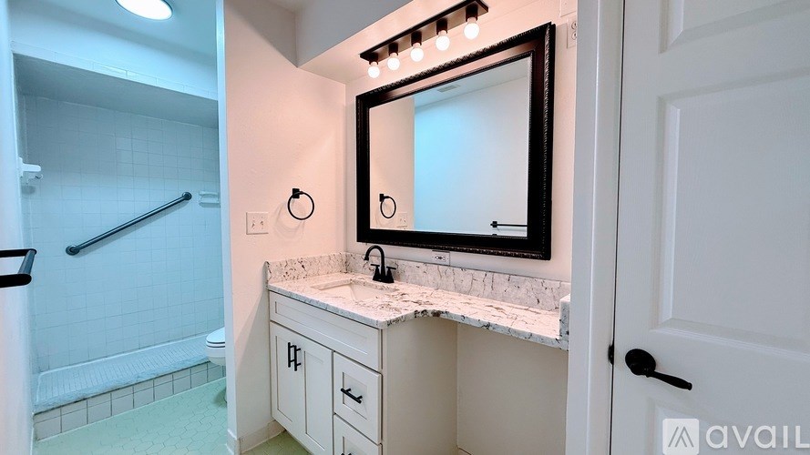 A bathroom with a marble countertop and a large mirror above it.