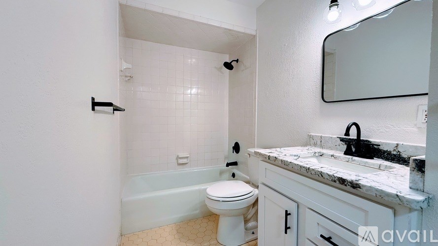 A bathroom with a white toilet, a marble countertop, and a white bathtub.