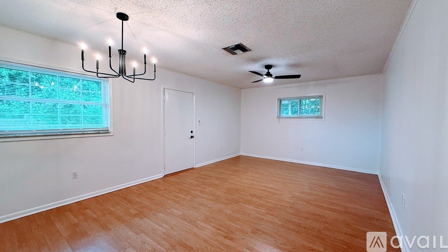 A room with wooden flooring and a window with blinds.
