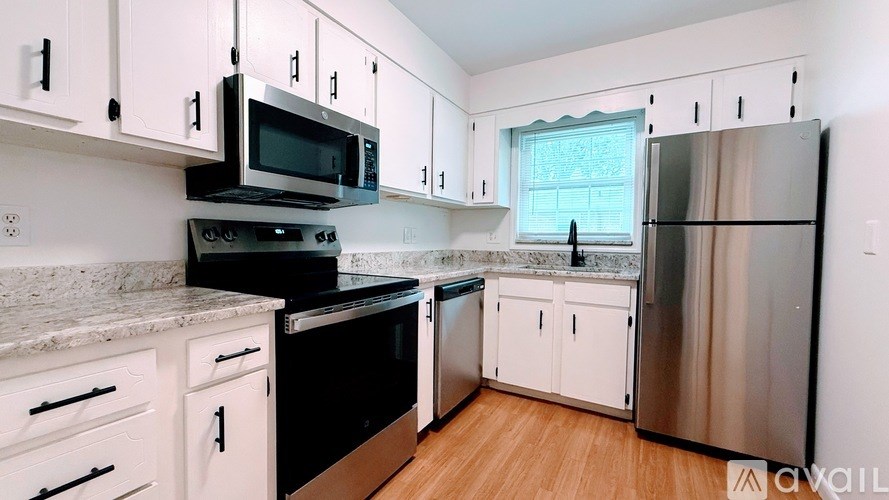 A kitchen with black appliances and white cabinets.