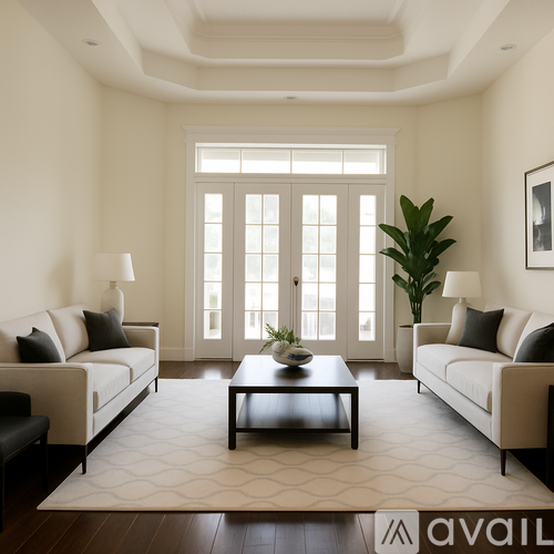 A living room with a white couch, a coffee table, and a large window.