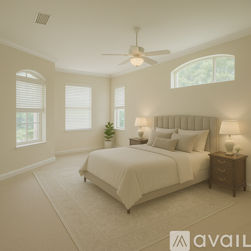 A bedroom with a large bed, a ceiling fan, and two lamps.