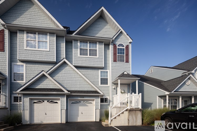 A two-story house with a garage and a car parked in front.