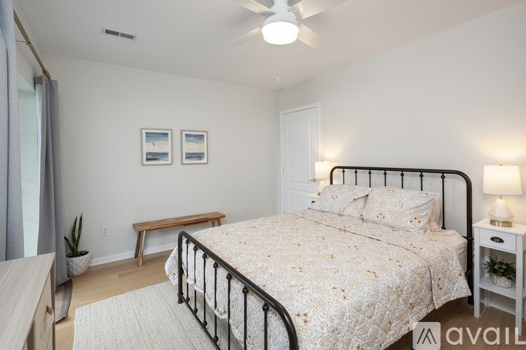 A bedroom with a bed, nightstand, and a plant.